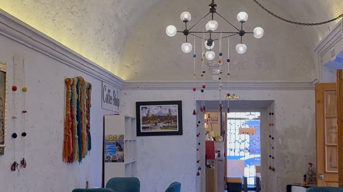 Salón de piedra abovedado con lámpara de araña en Aromas Caffee Arequipa